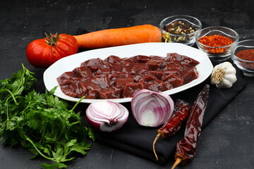 Cut raw beef liver with onions, spices, chili peppers and dill on wooden table, flat lay