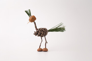 A handmade bird crafted from pine cones and twigs, on a white background, funny character made by...