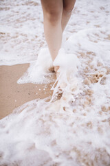 Close up picture of woman's legs washed by sea waves