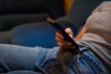 Enjoying a relaxing moment while seated on the couch, wearing jeans and using my phone