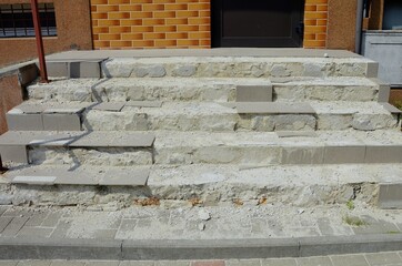 The crumbling staircase of the entrance to the building. Ruins, ceramic tiles falling off concrete stairs.