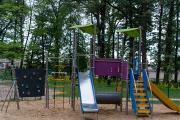 Modern colorful playground structure in a park surrounded by trees on an overcast day. Concept of outdoor activity, child development, and fun recreational spaces. High quality photo