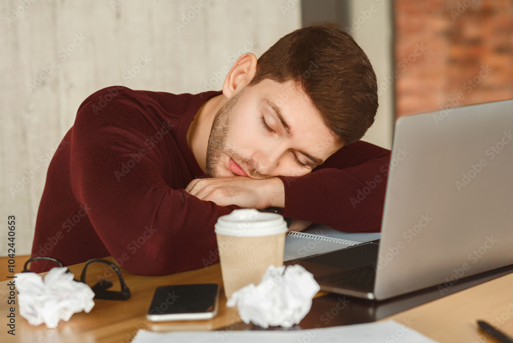 Poster exhausted man sleeping at laptop tired of multitasking and overworking sitting in office. selective 