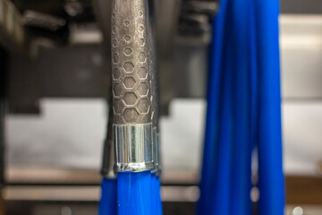 Close-up of a metallic nozzle with a honeycomb texture and blue tubing in an industrial setting
