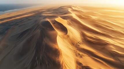 Aerial view of sand dunes at sunset, their flowing curves and contrasting shadows forming a beautiful, abstract landscape