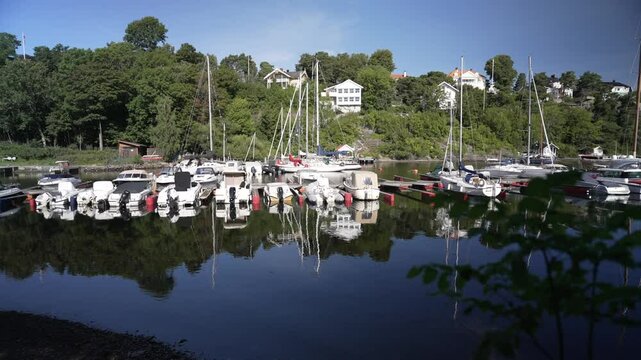 View of boats and houses reflecting in the water at Langviksbukta on a sunny day, Bygdoy, Oslo, Norway, Scandinavia, Europe