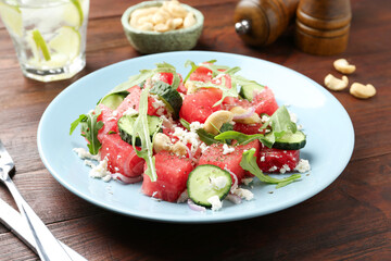 Tasty salad with watermelon, feta cheese, cashews and arugula on wooden table