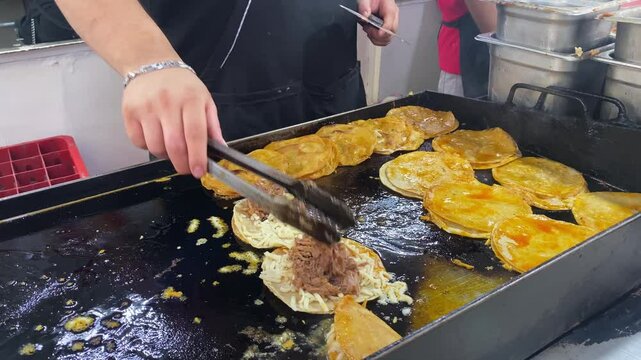 Chef prepares an order of tacos with meat and cheese at a Taqueria located in Roma Norte, Mexico City, Mexico.