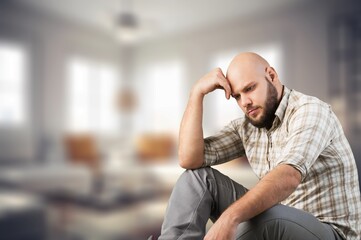 Fototapeta premium Stressed sad man sitting at home holding his head