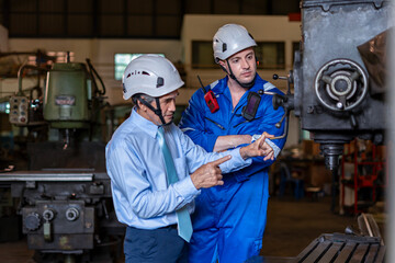 young caucasian technician talking with old experience manager who examining lathe machine,construction workers working in welding industry