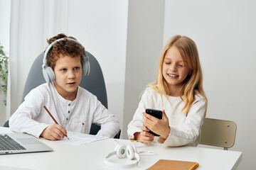 Happy children studying at home using laptops and headphones a boy and a girl engrossed in online elearning