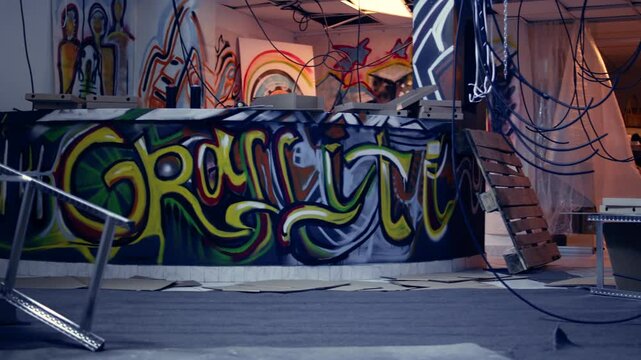 Empty derelict building with creative graffiti street art on walls, concept of alternative lifestyle. Dirty wrecked base of operations used by criminals to commit illegal activities, panning shot
