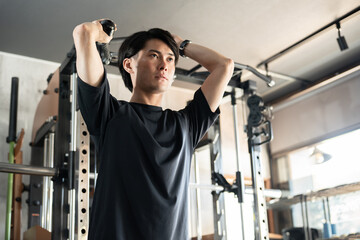 ジム・トレーニングジムで腕トレをする若いアジア人男性（腕トレ）

