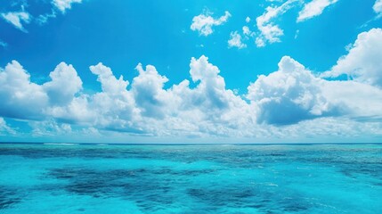 Obraz premium A serene ocean view under a bright blue sky with fluffy clouds.