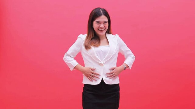 woman wearing white office suit smiling relieved after defecating, both hands holding and rubbing stomach, standing isolated red background, for health, science, promotion, education content