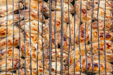 Close-up of chicken wings with hot sauce on a grill grate