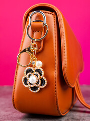 Close up of bright metal flower shaped rhinestone keychain on  brown  bag