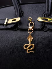 Naklejka premium bright pattern of an unforgettable metal keychain in the shape of a snake on black bag