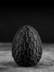 Close-up of a plastic egg model with ornament on a black background