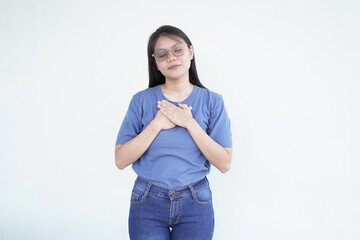 Beautiful Asian woman places her hand on her chest, symbolizing self-love and care, against a white...