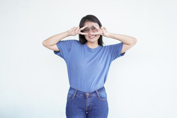 Beautiful Asian woman smiles warmly while flashing a peace or victory sign against a bright white background