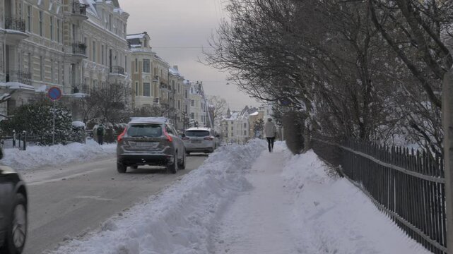 Streets of Oslo covered in snow in a cold winter day. Nordic houses blanketed in snow, capturing the calm and simplicity of winter. Filmed in Downtown Oslo, Norway.