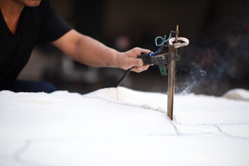Garment workers cutting polyester fiber for filling of cotton jackets
