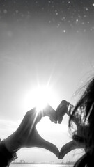 Obraz premium Hands forming a heart against the sun in a black and white minimalist concept.