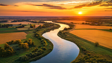 A picturesque image of a winding river bordered by golden fields, reflecting the colors of the sky at sunset.