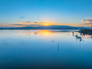 Sunrise waterscape over the bay with birdlife and smoke haze