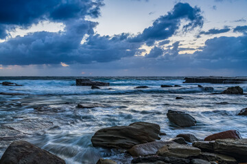 Moody sunrise seascape with clouds at the rocky inlet