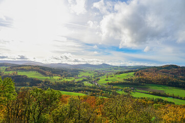 Naklejka premium Autumn panoramic view of the beautiful landscape of the Hessian Rhön, with autumn forests, meadows and a small village near Hilders, autumn leaves, Hilders, Hesse, Germany 
