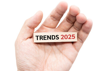 Text TRENDS 2025 wooden block on hand with Clipping path isolated on white background. marketing monitor, business planning.