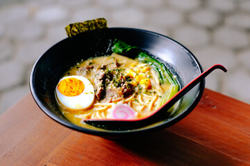 A delicious bowl of ramen noodles topped with a soft-boiled egg, beef, nori, and vegetables.