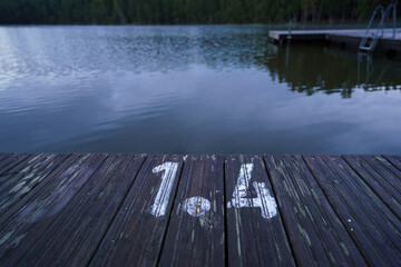 Wooden dock displaying the depth marked 1.4 meters on a calm lake