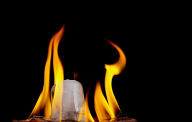 ice cube burning in fire isolated on black background with copy space