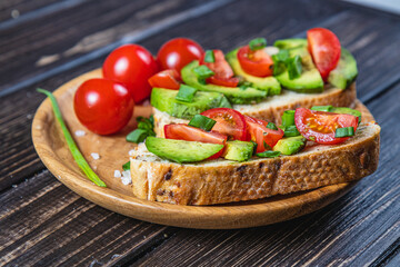 Avocado toast topped with tomato and green onion on a slice of carrot bread