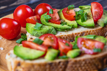 Avocado toast topped with tomato and green onion on a slice of carrot bread
