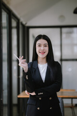 Professional Asian businesswoman using mobile phone and laptop in office