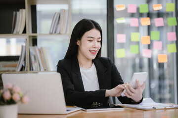 Asian woman using calculator to calculate financial expenses in home office. Pressing calculator button to analyze finances, electronic payments.