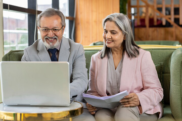 Executive discussing with senior professional while working on laptop at office