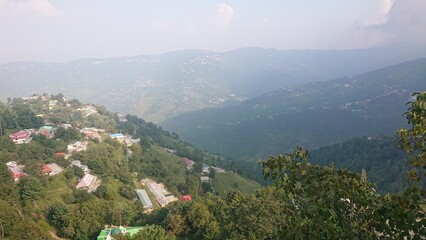 Naklejka premium View of village in the hills from top with layers of mountains