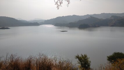panoramic view of a calm lake with misty hills