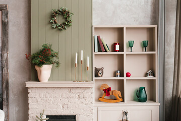 Beige fireplace mantel with christmas wreath and wooden rocking horse in living room
