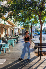 girl in stylish clothes walking in the city.  young cheerful woman smiling and looking at the camera.