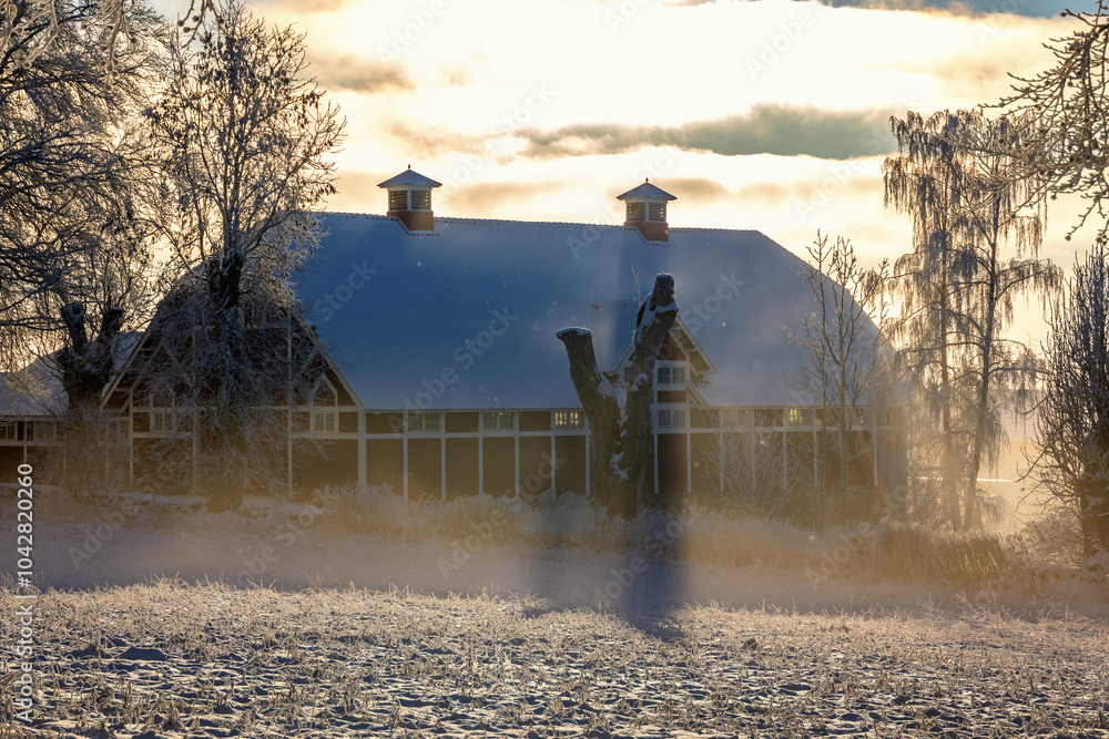 Poster Backlit barn in the winter in a snowfall