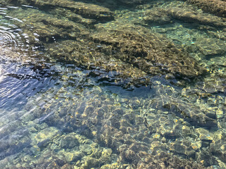 Sea clear transparent water with stones pebbles at the bottom