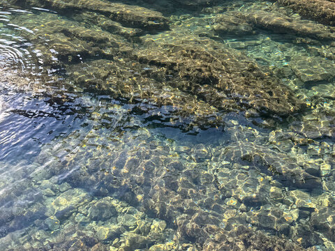 Sea clear transparent water with stones pebbles at the bottom