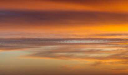 A glowing orange-gold sunset over a calm sky filled with fluffy clouds.A glowing orange-gold sunset over a calm sky filled with fluffy clouds.
