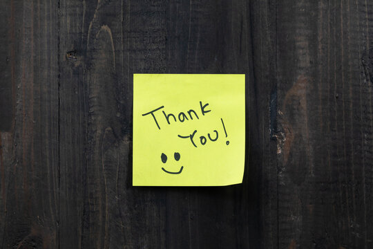 Positive idea concept image using a wooden table and a sticky note with the words Thank you